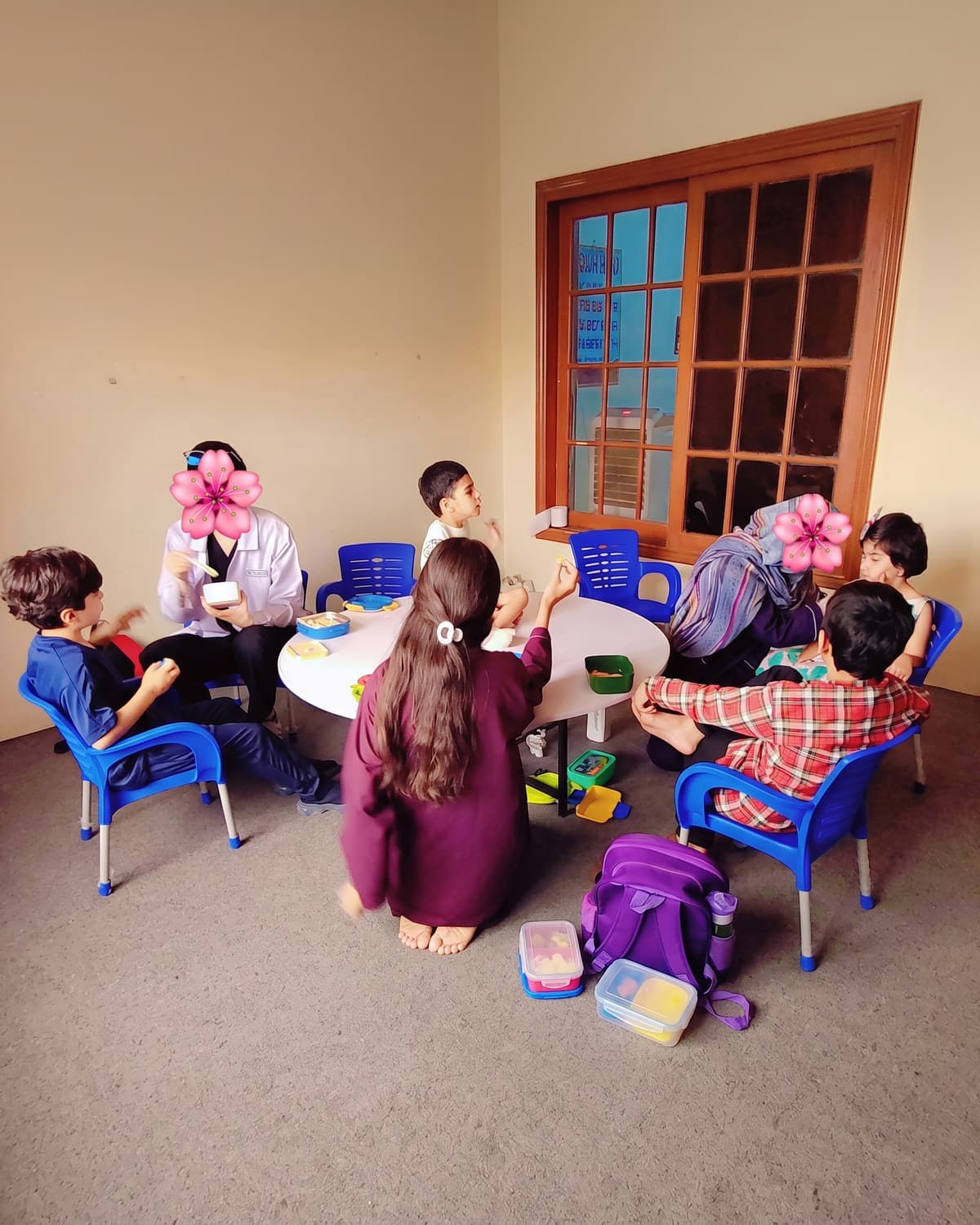 Snack time around the round table, lunchboxes open and a teacher helping